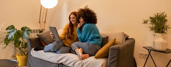 Two people cozying up on a couch, watching content on a tablet